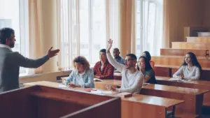 Student zgłasza się do odpowiedzi podczas zajęć w sali wykładowej na uniwersytecie.