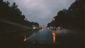 Samochody jadące przez mokrą autostradę podczas ulewnego deszczu w pochmurny dzień.