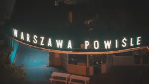 Podświetlony neon z napisem Warszawa Powiśle w nocy, widok z góry na plac