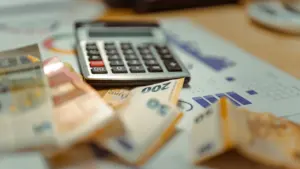 Kalkulator i banknoty euro leżące na stosie dokumentów i paragonów w biurze